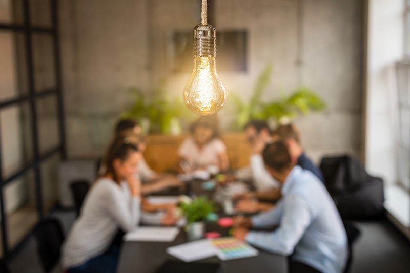 Young business people are discussing together a new startup project. A glowing light bulb as a new idea.