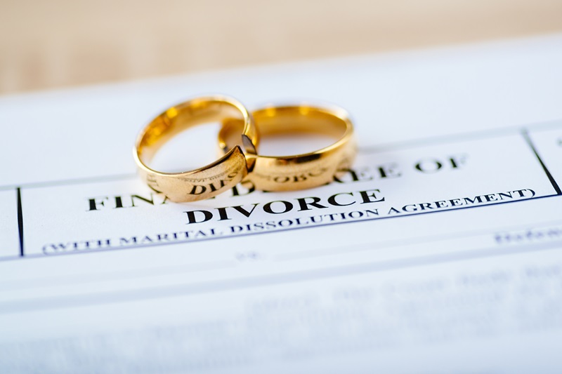 Two broken golden wedding rings divorce decree document. Divorce and separation concept